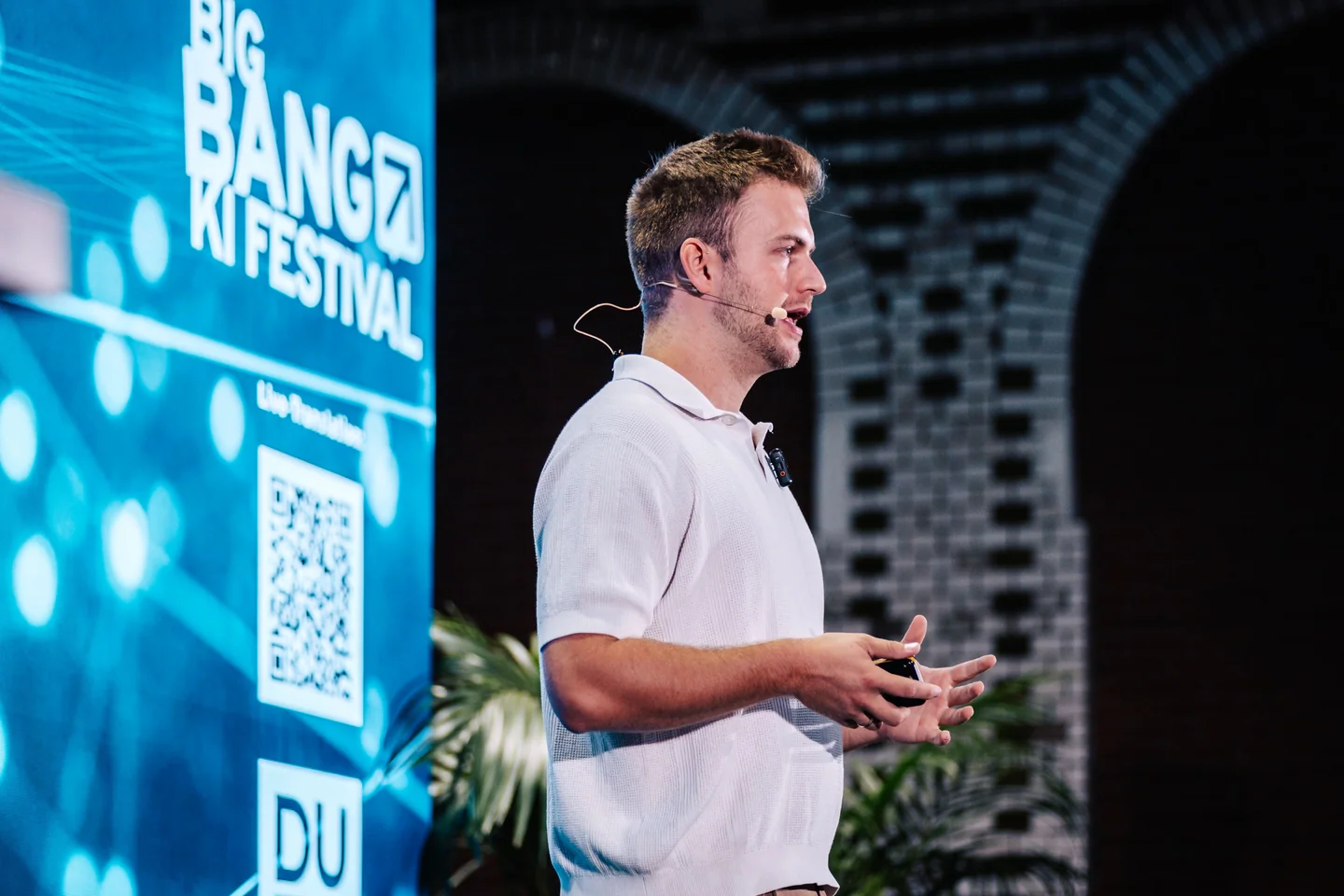 Marco Heer erklärt mit offenen Händen einen Gedanken beim BIG BANG KI Festival