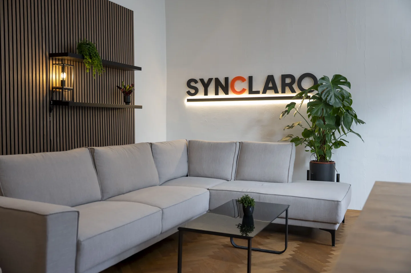 Sitzbereich im Synclaro-Büro mit beleuchtetem Logo