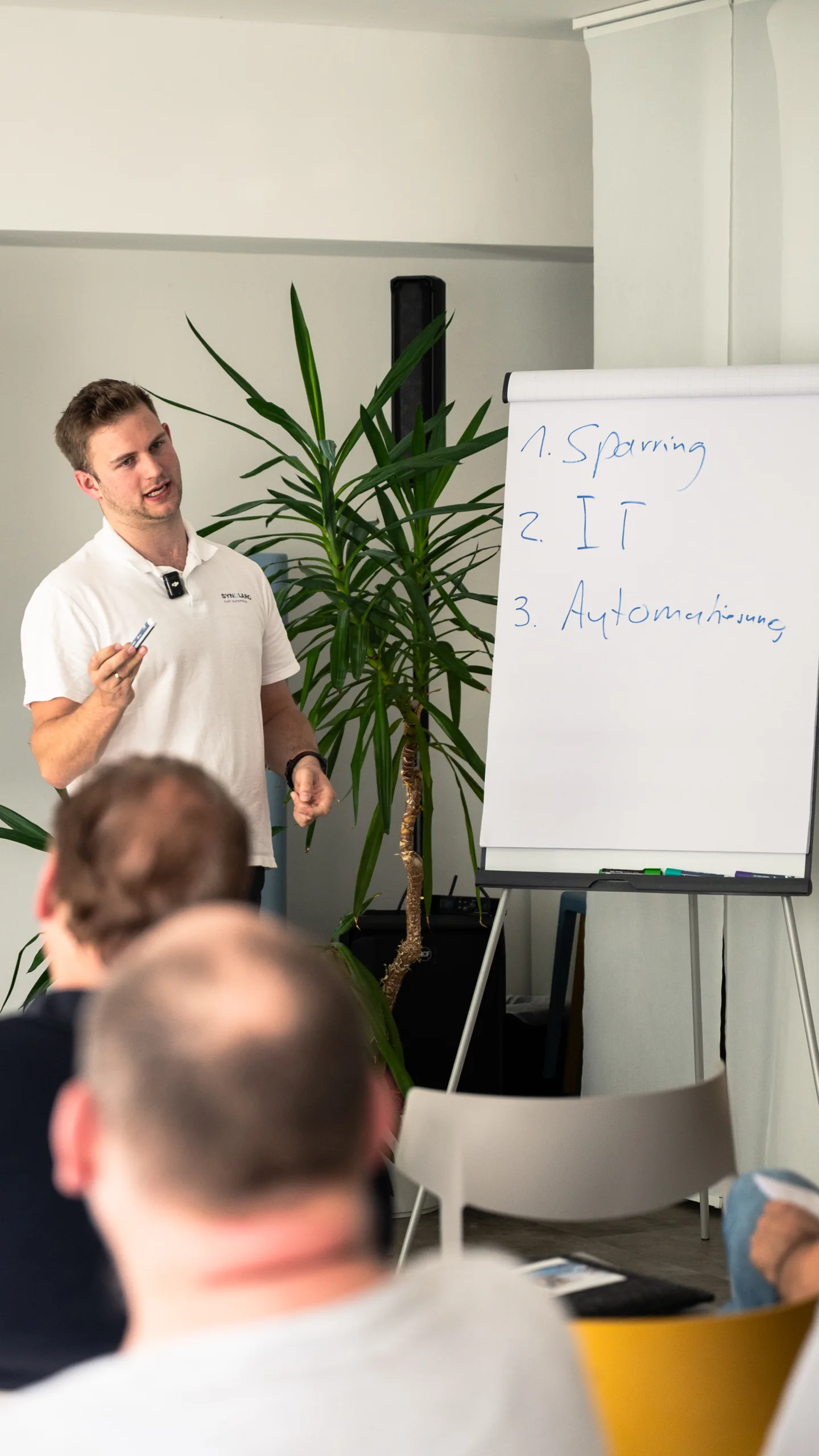 Marco im Austausch mit den Teilnehmenden neben einem Flipchart
